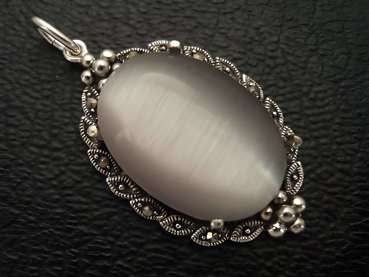 Cabochon Katzenauge grau in einem silbernen Medaillon Anhänger, Hersteller Juwelier Harnisch, mit dekorativem Design und glänzender Oberfläche. Perfekt für elegante Schmuckstücke.