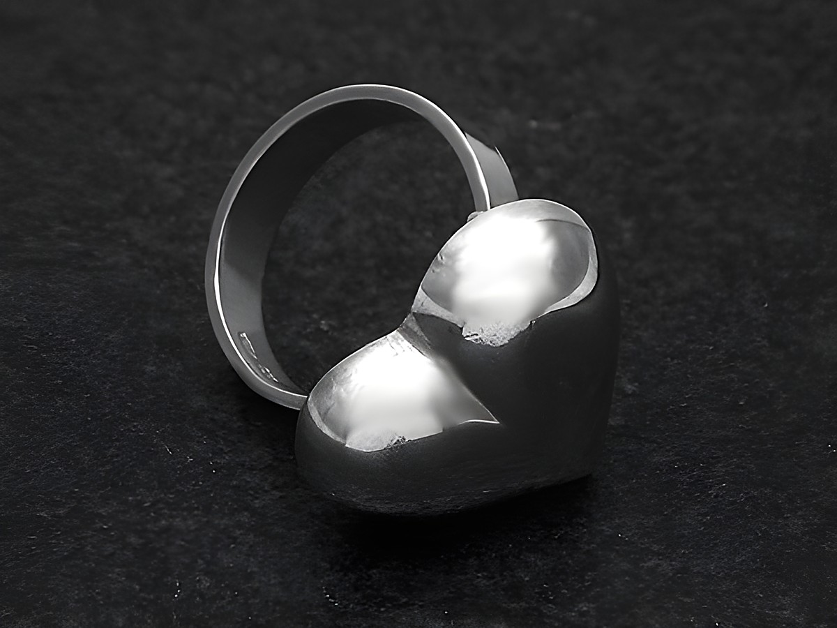 Silberring in Herzform, plastisch gestaltet, Größe weit verstellbar, Hersteller Juwelier Harnisch, ohne Stein, auf schwarzem Hintergrund.