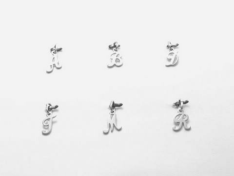 925 Silber Buchstaben Anhänger in Schreibschrift des Herstellers Juwelier Harnisch, im Vordergrund der Buchstabe I, umgeben von weiteren Buchstabenanhängern.
