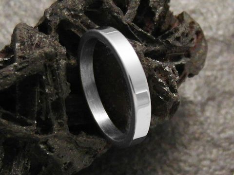 Edelstahlring Gr. 17/54,0 flach 3 mm poliert massiv Hersteller Juwelier Harnisch, auf einem dunklen Untergrund abgebildet, glänzende Oberflächenstruktur.