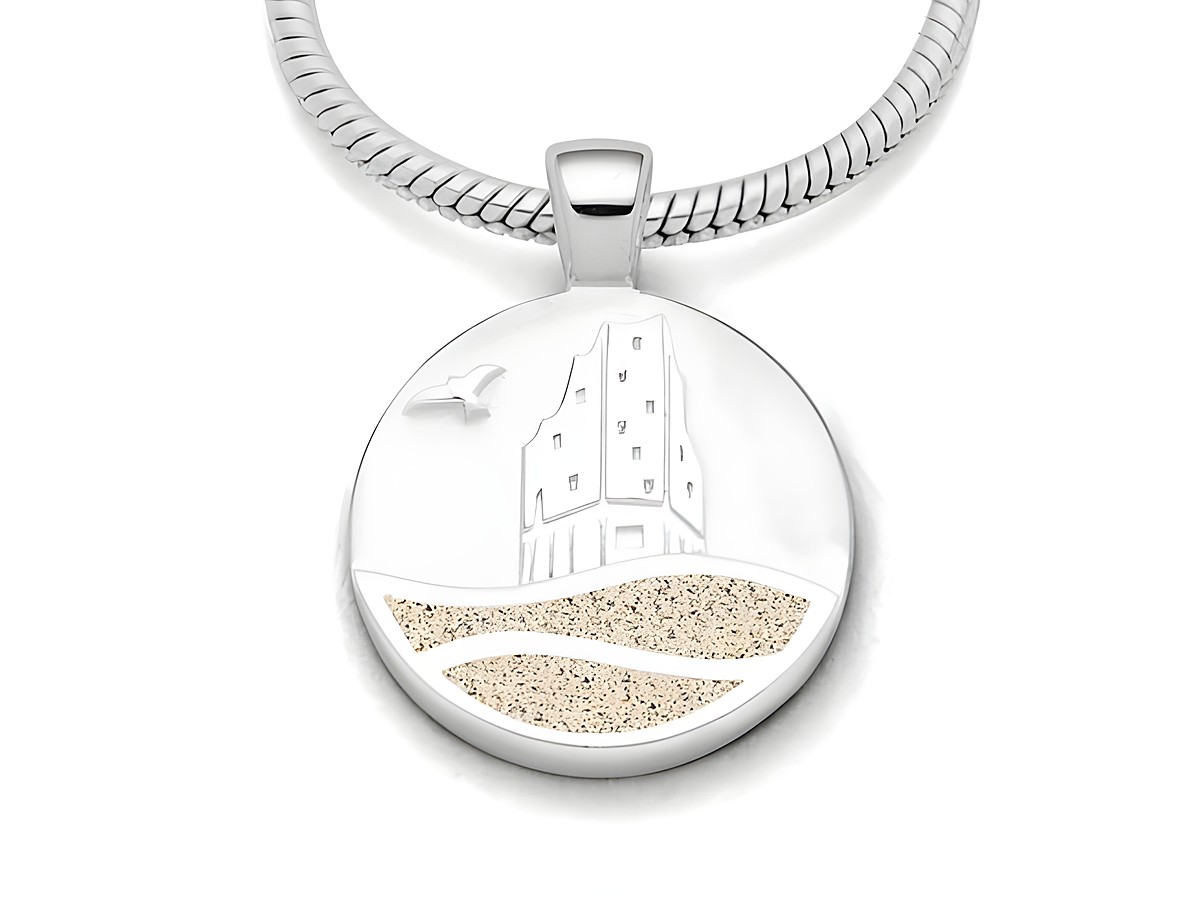 Ein runder Anhänger aus rhodiniertem Sterling Silber mit einer reliefartigen Darstellung eines Gebäudes und Wellen, gefüllt mit feinem Strandsand in Beige.