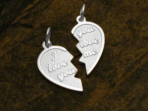 Zwei hängende Partnerherz Anhänger aus Sterling Silber, die in der Mitte geteilt sind und die Inschriften I love you und you love me tragen, ideal als Liebessymbol von Juwelier Harnisch.