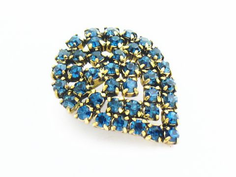 Blaue Strass Brosche im sexy City Look in Form eines Blattes, Hersteller Juwelier Harnisch, verziert mit funkelnden blauen Strasssteinen in goldfarbener Fassung.