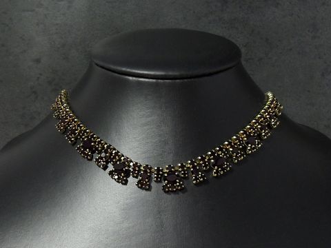 Strass Kette reizend in granatrot von 45 bis 48,5 cm, goldfarbene Fassung, Hersteller Juwelier Harnisch, elegant und funkelnd auf schwarzem Hintergrund präsentiert.