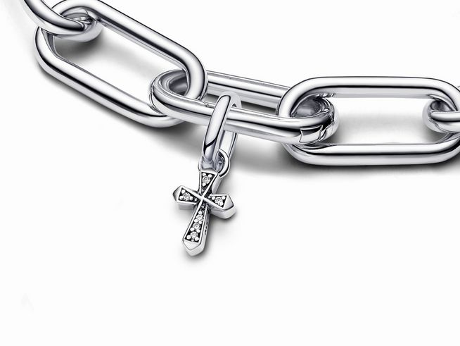 Ein Trend-Charm von Pandora, ein Mini-Anhänger in Form eines Kreuzes aus Sterling Silber mit funkelnden Zirkonia, hängt an einer glatten Silberkette.