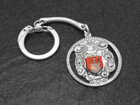 Nostalgischer Schlüsselanhänger mit dem Hamburg Wappen, silberfarben und von Juwelier Harnisch gefertigt, zeigt detaillierte Ornamente und das rote Hamburg Wappen.