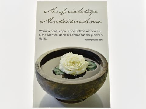 Trauerkarte mit der Aufschrift Aufrichtige Anteilnahme und einem Zitat von Michelangelo. Im Vordergrund eine weiße Rose in einer runden Schale mit Wasser.