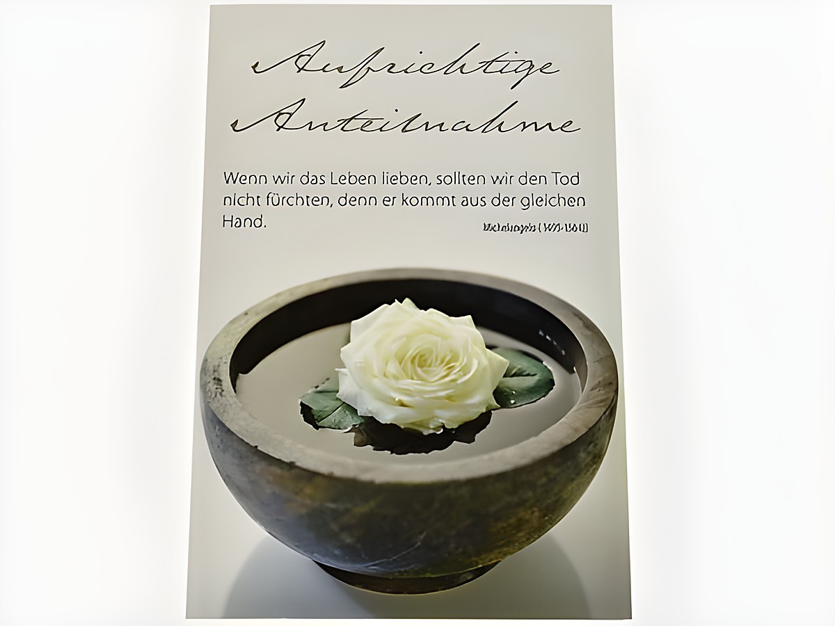 Trauerkarte mit der Aufschrift Aufrichtige Anteilnahme und einem Zitat von Michelangelo. Im Vordergrund eine weiße Rose in einer runden Schale mit Wasser.