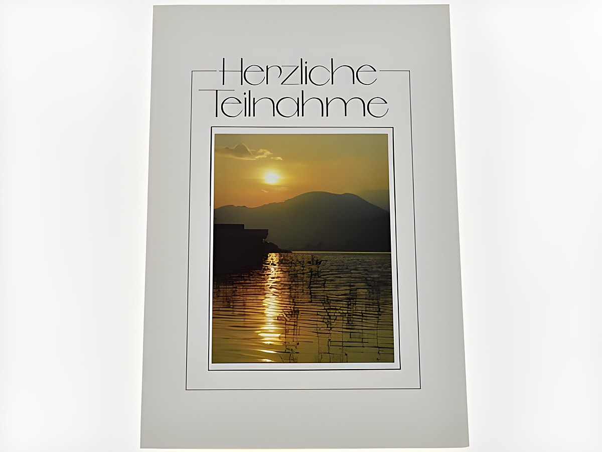 Trauerkarte mit einer friedlichen Landschaft, die See, Berge und eine untergehende Sonne zeigt, sanfte Farben strahlen Ruhe und Trost aus. Hersteller: Juwelier Harnisch.