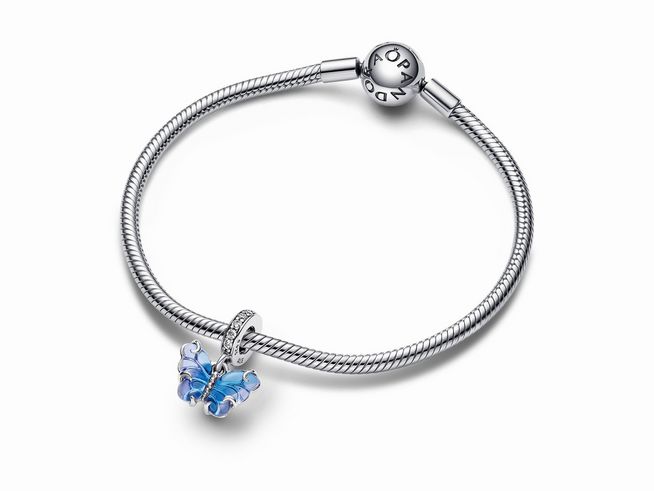 792698000-1 Ein blauer Murano-Glas Schmetterlings Charm-Anhänger aus Sterling Silber von Pandora, der an einem klassischen Silberarmband befestigt ist. Die filigranen Details und die leuchtenden Farben setzen einen eleganten Akzent.