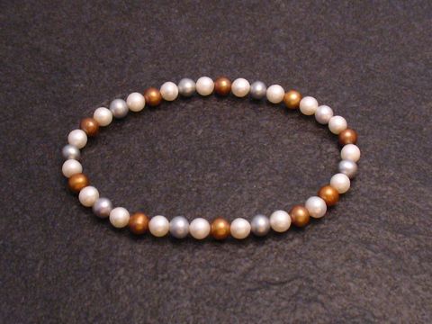 Perlenarmband 5,3 mm in Weiß-gold-grau mit Gummizug, Länge 18 cm, Hersteller Juwelier Harnisch, elegante Anordnung der Perlen auf schwarzem Hintergrund.