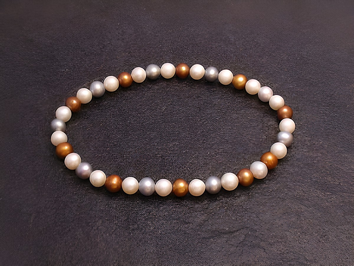 Perlenarmband 5,3 mm in Weiß-gold-grau mit Gummizug, Länge 18 cm, Hersteller Juwelier Harnisch, elegante Anordnung der Perlen auf schwarzem Hintergrund.