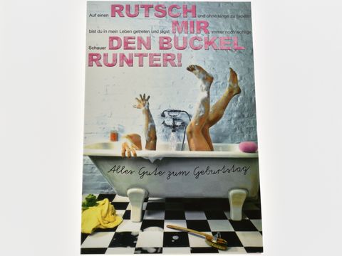 Eine farbenfrohe Geburtstagskarte mit dem Bild einer Badewanne und zwei Beinen, die aus der Wanne ragen. Der lustige Spruch fordert dazu auf, den Buckel runterzurutschen. Hersteller ist Juwelier Harnisch.