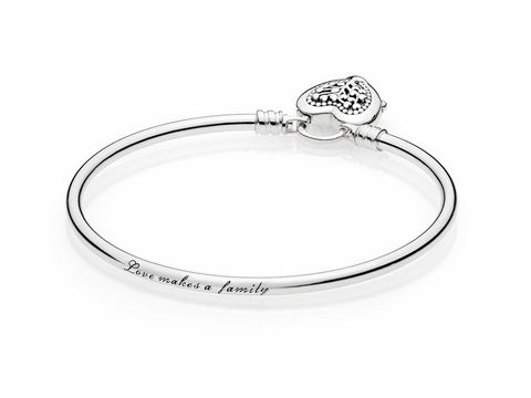 Ein eleganter Silberarmreif von Pandora mit einem Herzcharm und der Gravur "Love makes a family", Teil der Flourishing Hearts Kollektion, Länge 19 cm.