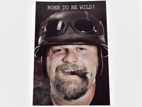 Männergesicht mit Helm und Zigarre, erfreulich grinsend, mit Aufschrift Born to be wild, vom Juwelier Harnisch, geeignet für Grußkarten.