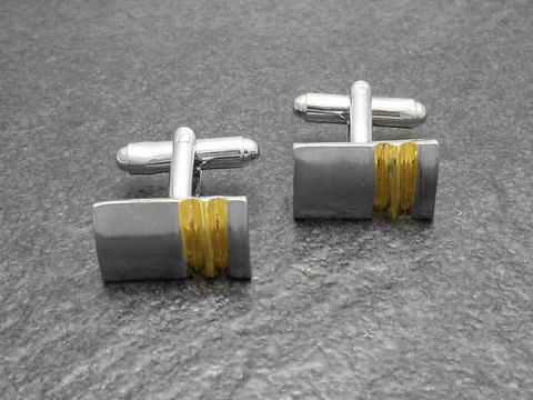Moderne Manschettenknöpfe in Bi-Color silber-goldfarben von Juwelier Harnisch, silverfarbener Look mit goldfarbener Akzentlinie, elegant und stilvoll für besondere Anlässe.