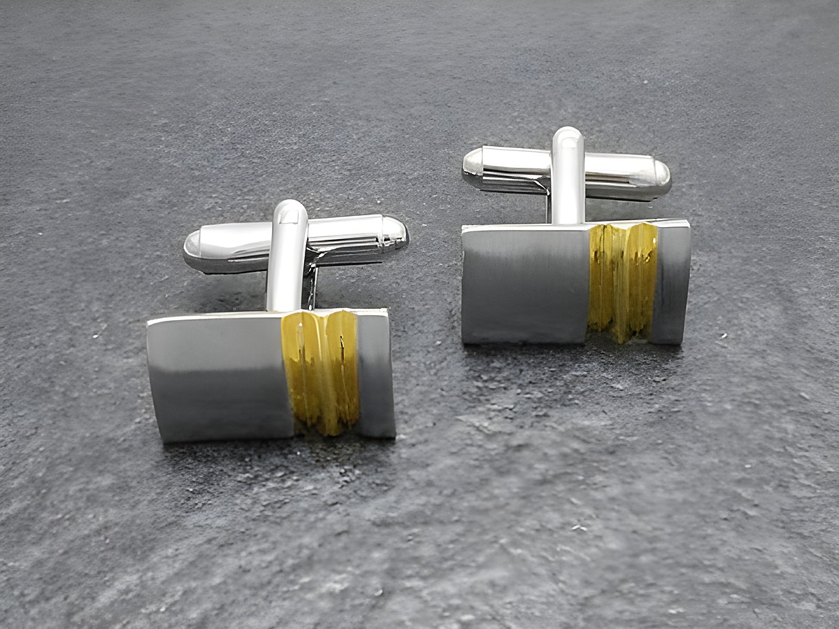 Moderne Manschettenknöpfe in Bi-Color silber-goldfarben von Juwelier Harnisch, silverfarbener Look mit goldfarbener Akzentlinie, elegant und stilvoll für besondere Anlässe.
