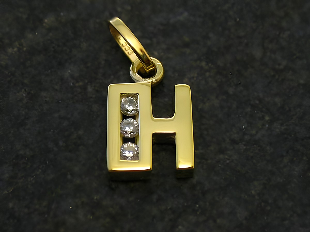 Goldener Anhänger in Form des Buchstabens H mit drei Zirkonia-Steinen. Hersteller Juwelier Harnisch. Ideal als persönliches Geschenk oder modisches Accessoire.
