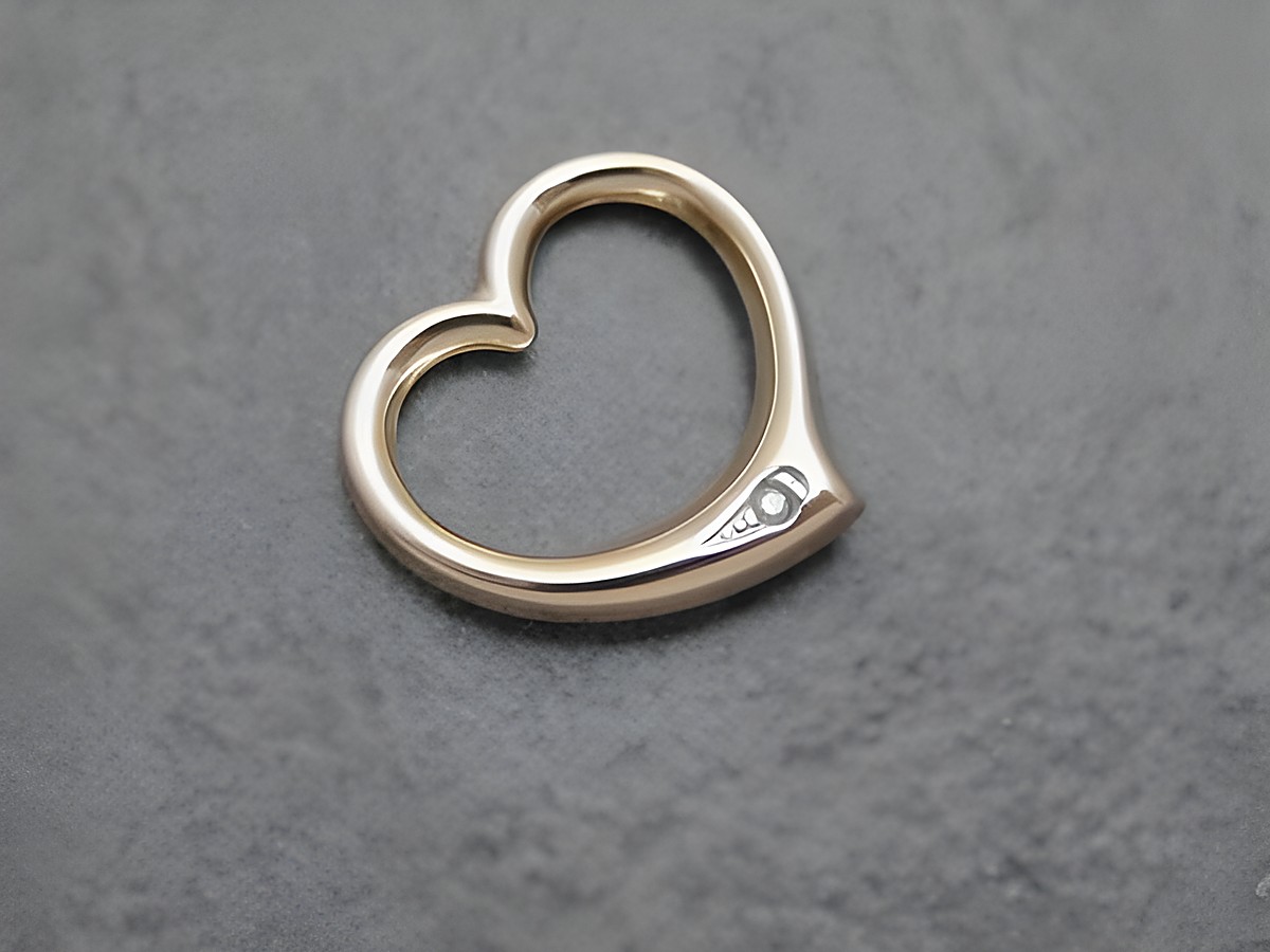 Goldener Herz-Anhänger mit durchlaufendem Design und Diamant, hergestellt von Juwelier Harnisch, ideal für besondere Anlässe.