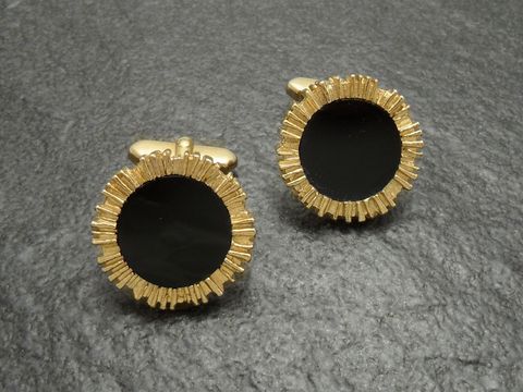 Vergoldete Manschettenknöpfe mit schwarzem Onyx-Look, umrandet von einer goldfarbenen Struktur, Hersteller Juwelier Harnisch, elegant und stilvoll für besondere Anlässe.
