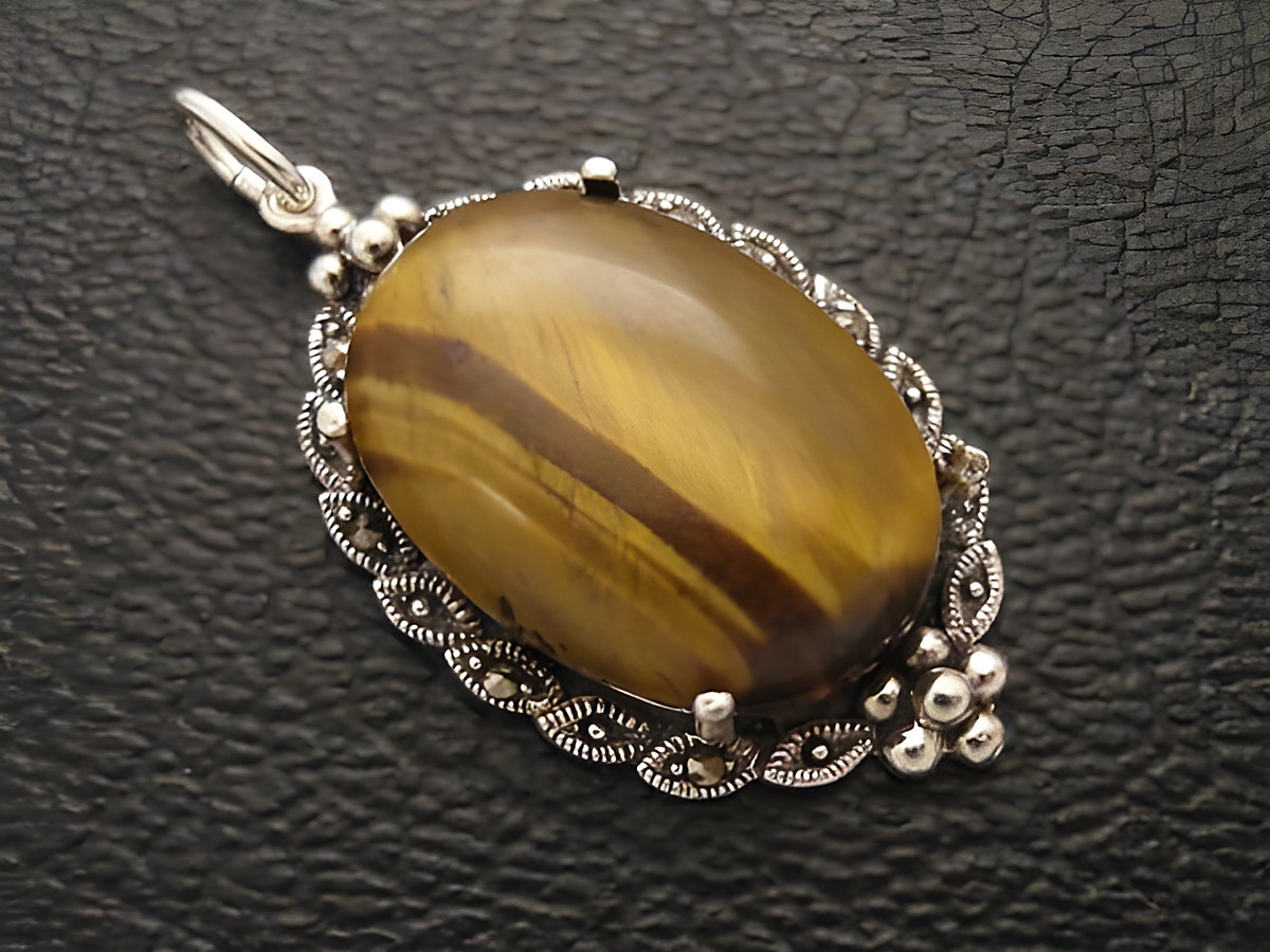 Cabochon Tigerauge in ovaler Form, eingefasst in ein filigranes Silber Medaillon, Hersteller Juwelier Harnisch, schimmernde Oberflächenstruktur und elegante Gestaltung.