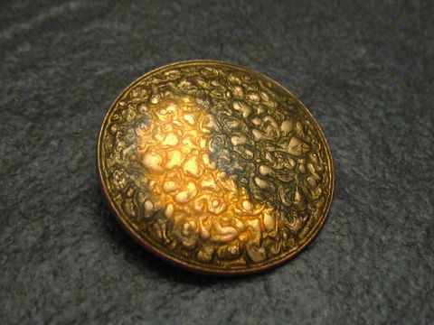 60909-0 Eine goldfarbene Emaille Brosche mit einem strukturierten Muster und einem vintage Design, gefertigt vom Juwelier Harnisch, ideal für stilvolle Akzente.