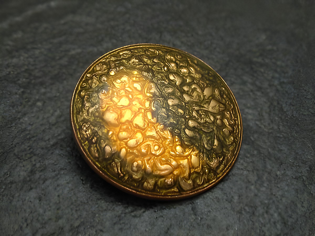 Eine goldfarbene Emaille Brosche mit einem strukturierten Muster und einem vintage Design, gefertigt vom Juwelier Harnisch, ideal für stilvolle Akzente.