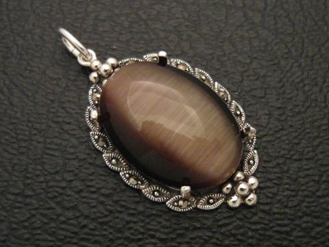 Cabochon Katzenauge braun in einem Silber Medaillon Anhänger von Juwelier Harnisch, filigran gearbeitet mit dekorativen Elementen um den Stein.