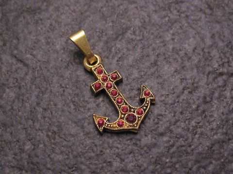 Roter Strass Anhänger in Form eines Ankers, glänzende goldfarbene Oberfläche, verziert mit roten Strasssteinen, ideal für einen sexy City Look, Hersteller Juwelier Harnisch.