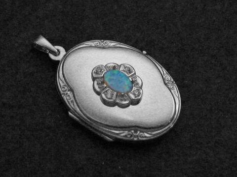 Medaillon aus rhodiniertem Sterling Silber mit einem ovalen Opal Cabochon, umgeben von einer blütenförmigen Ornamentik und feinen Details. Ideal für Anhänger oder Schmuckdesign.