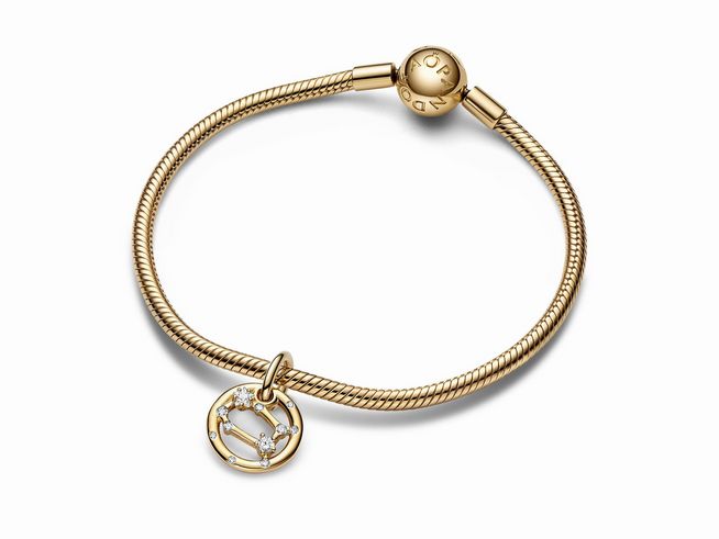 Ein eleganter Charm-Anhänger mit dem Sternzeichen Zwillinge aus vergoldetem Silber, verziert mit Zirkonia, an einer feinen Armbandkette von Pandora in Gelbgold.