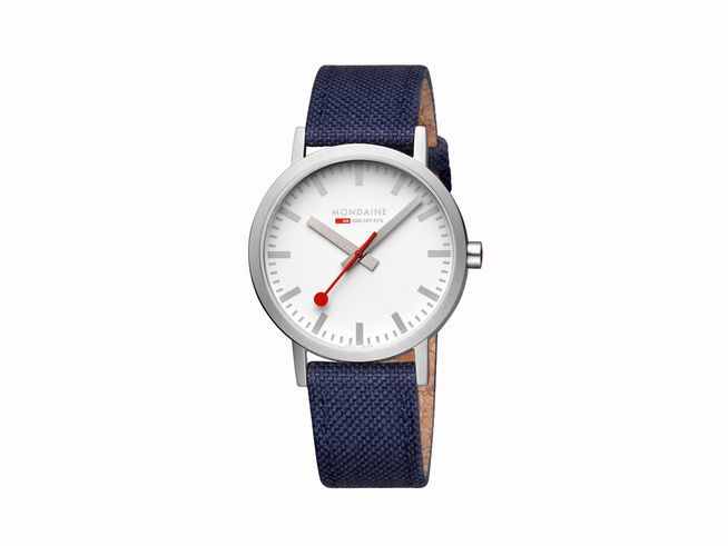Mondaine Classic A660.30360.17SBD1 Armbanduhr mit einem 40 mm Gehäuse, weißem Zifferblatt, roten Zeigern und einem blauen Textilarmband. Elegant und modern gestaltet.
