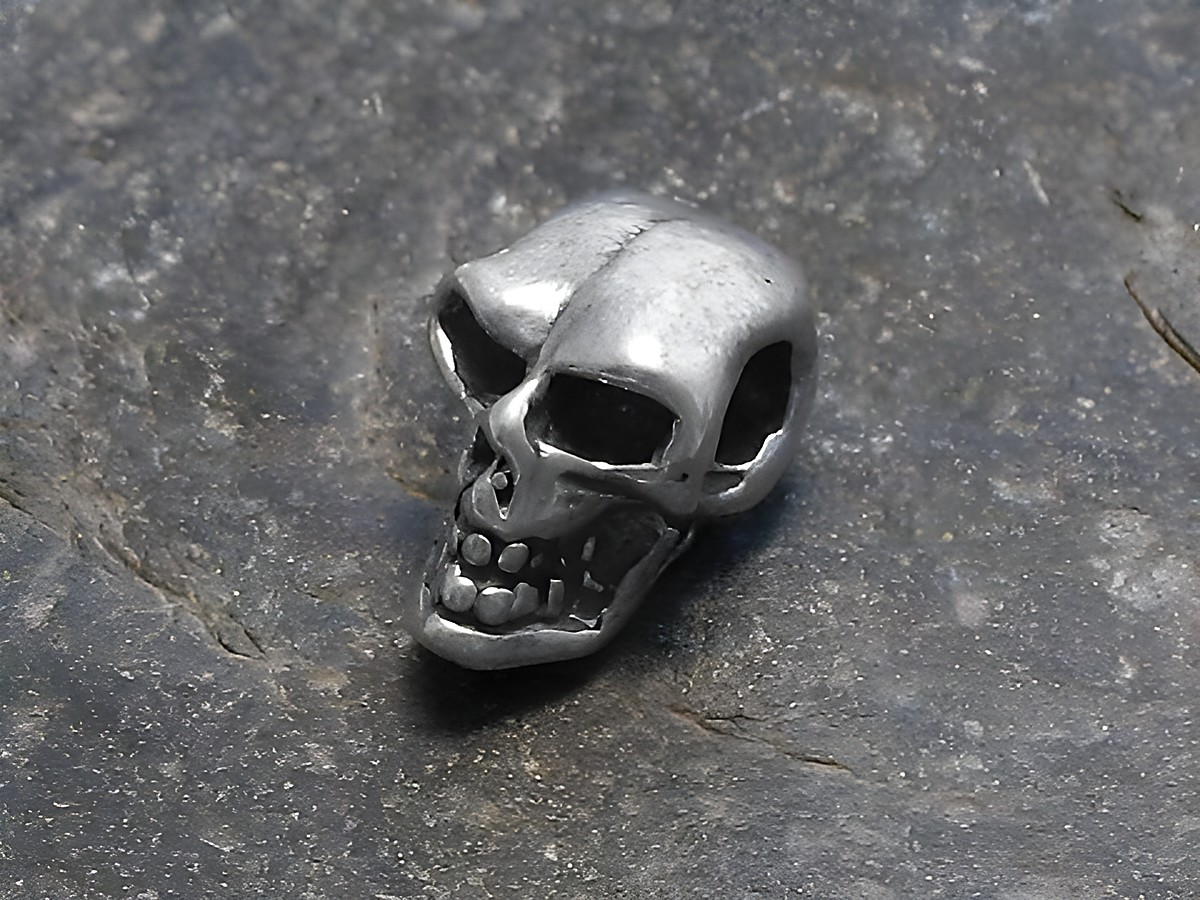 Totenkopf - 925 Sterling Silber Anhänger - klein - Hersteller: Juwelier Harnisch, detailreiche Darstellung eines kleinen Totenkopfes aus Silber auf grauem Hintergrund.