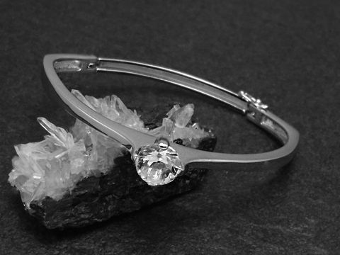 Silber Armreifen edel 11,2 mm rhodiniert 17 cm Hersteller Juwelier Harnisch mit strahlendem Stein, auf dunklem Hintergrund und in eleganter Präsentation.