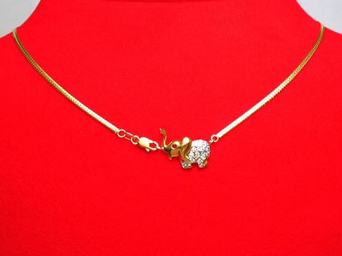 Collier 333 mit Mittelteil in Form eines bicolor Elefanten, besetzt mit Zirkonia und Saphir, auf rotem Hintergrund liegend. Schmuckstück von Juwelier Harnisch, Länge 45 cm.