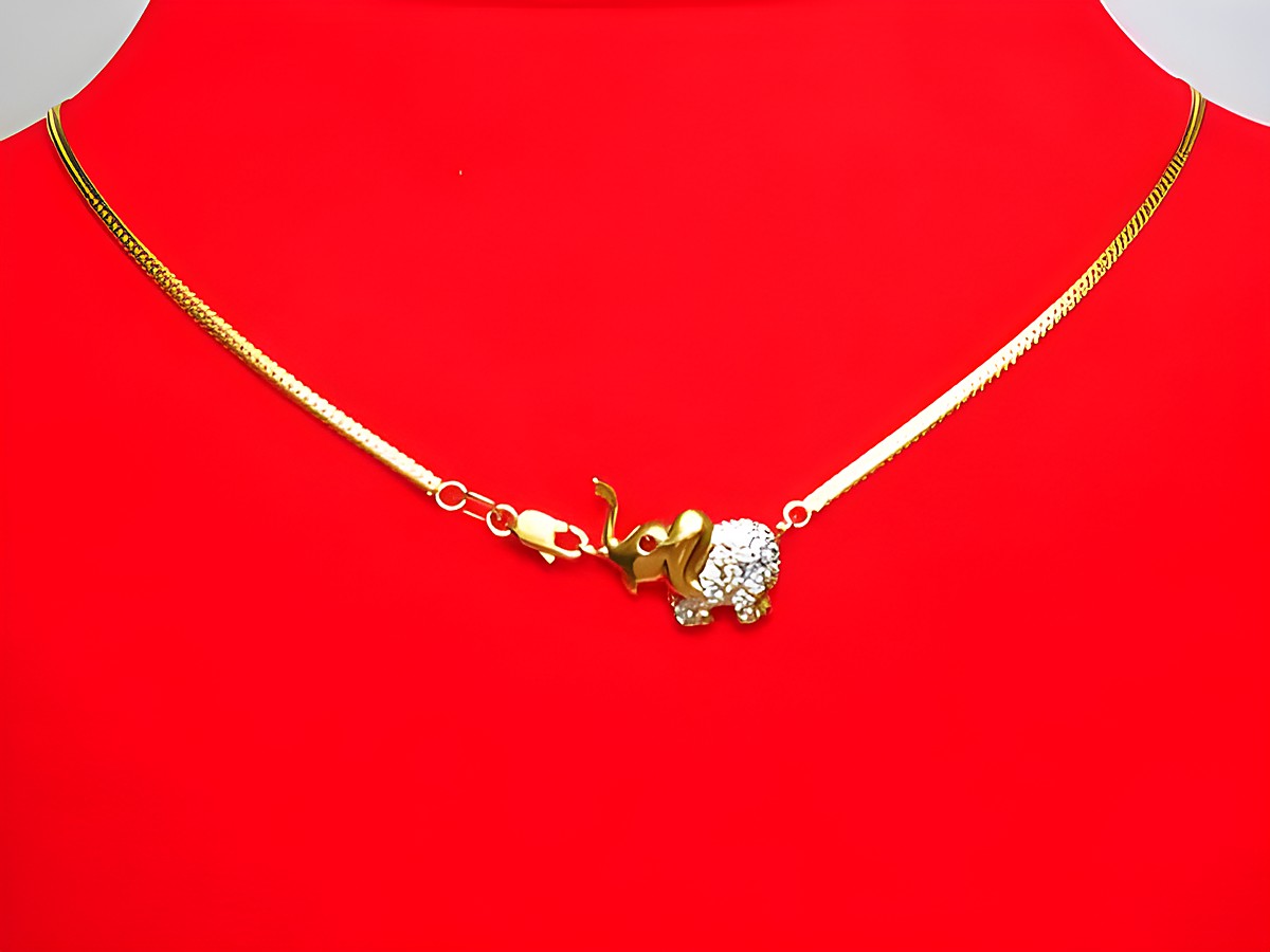 Collier 333 mit Mittelteil in Form eines bicolor Elefanten, besetzt mit Zirkonia und Saphir, auf rotem Hintergrund liegend. Schmuckstück von Juwelier Harnisch, Länge 45 cm.
