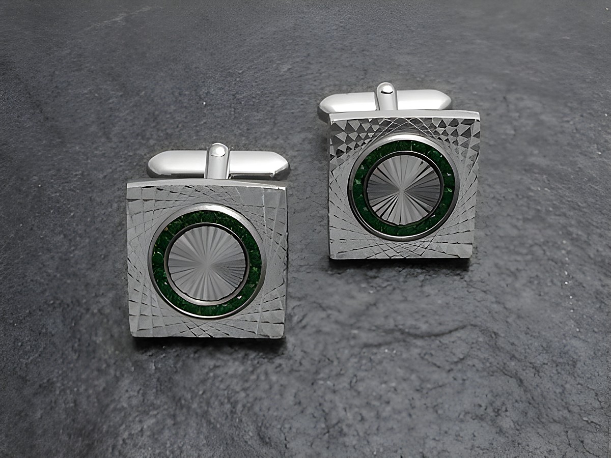 Manschettenknöpfe in Silberfarbe mit feinem grünen Strass von Juwelier Harnisch, verziert mit Strasssteinen und einem eleganten, eingefrästen Muster.