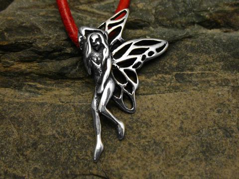 Ein filigraner Anhänger aus Sterling Silber in Form einer Elfe mit weit ausgestreckten Flügeln, auf einem roten Lederband, vor einer naturbelassenen Unterlage.