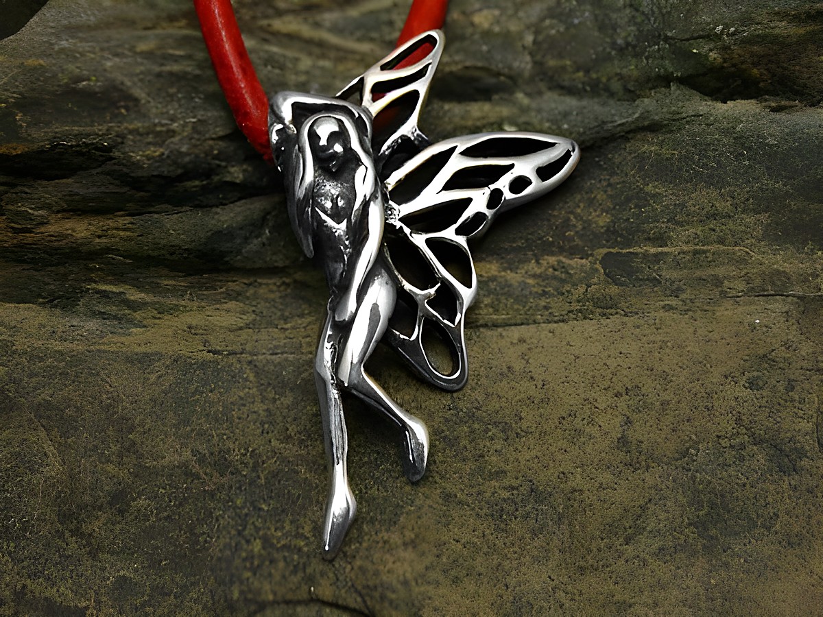 Ein filigraner Anhänger aus Sterling Silber in Form einer Elfe mit weit ausgestreckten Flügeln, auf einem roten Lederband, vor einer naturbelassenen Unterlage.