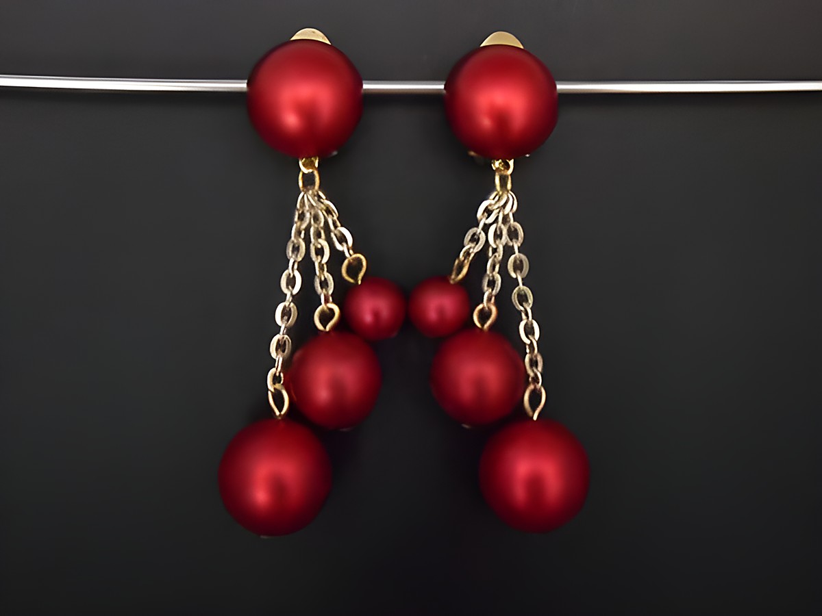 Dunkelrote Ohrclips aus Kunstharz mit goldfarbenem Detail, zeitloses Design, hängen mit feinen Ketten, elegant und edel, Hersteller Juwelier Harnisch.