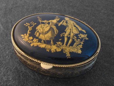 Multifunktionale Dose mit ovaler blauer Einlage und goldfarbenem Aufdruck, Hersteller Juwelier Harnisch, ohne Stein, romantisches Motiv von tanzenden Figuren umgeben von floralen Elementen.