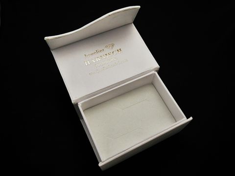 Geschenkschachtel für Trauringe und Manschettenknöpfe, viereckig und klassisch in weiß, Hersteller Juwelier Harnisch, elegant geöffnet und bereit zur präsentiere.