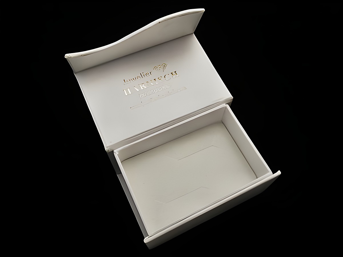 Geschenkschachtel für Trauringe und Manschettenknöpfe, viereckig und klassisch in weiß, Hersteller Juwelier Harnisch, elegant geöffnet und bereit zur präsentiere.