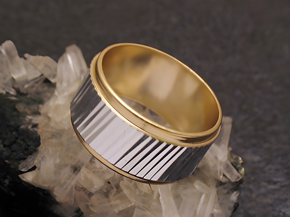 Bicolor City Party Ring 9,7 mm breit in Größe 56 / 18 mm, hergestellt von Juwelier Harnisch, mit streifenförmiger Oberfläche auf schwarzem Untergrund.
