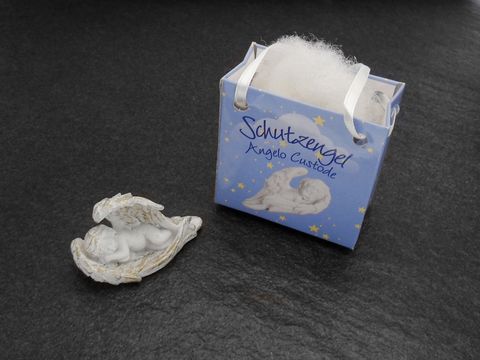 Schutzengel mit Geschenktasche liegend links, hergestellt von Juwelier Harnisch, ideal für Weihnachten. Die Figur zeigt einen Engel in zartem Design.