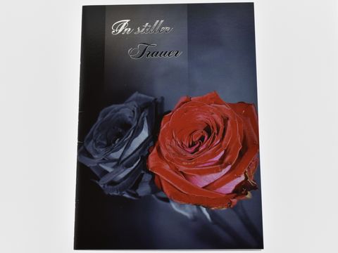 Auf der Trauerkarte sind eine schwarze und eine rote Rose abgebildet, mit dem Schriftzug In stiller Trauer. Hersteller ist Juwelier Harnisch, Trauerkarten.