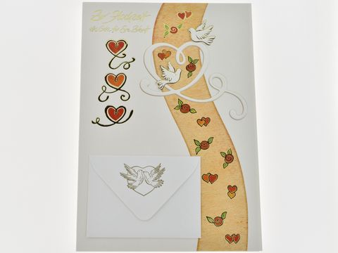 Zwei weiße Täubchen fliegen über einem dekorativen Herzmotiv auf einer Hochzeitskarte von Juwelier Harnisch, umgeben von bunten Herzen und einem eleganten Umschlag.