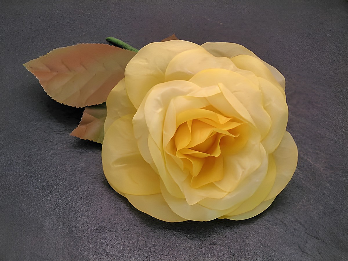 Haarschmuck mit einer opulenten gelben Textilrose und grünen Blättern, ideal als Brosche, hergestellt von Juwelier Harnisch, verleiht jedem Outfit eine elegante Note.