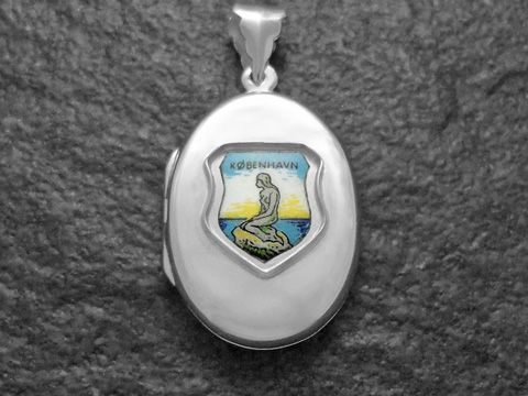 Silbernes Medaillon mit dem Motiv der Meerjungfrau von Kopenhagen, umgeben von einem bunten Hintergrund, Schlüsselanhänger von Juwelier Harnisch, ideal für Memento und Sammler.