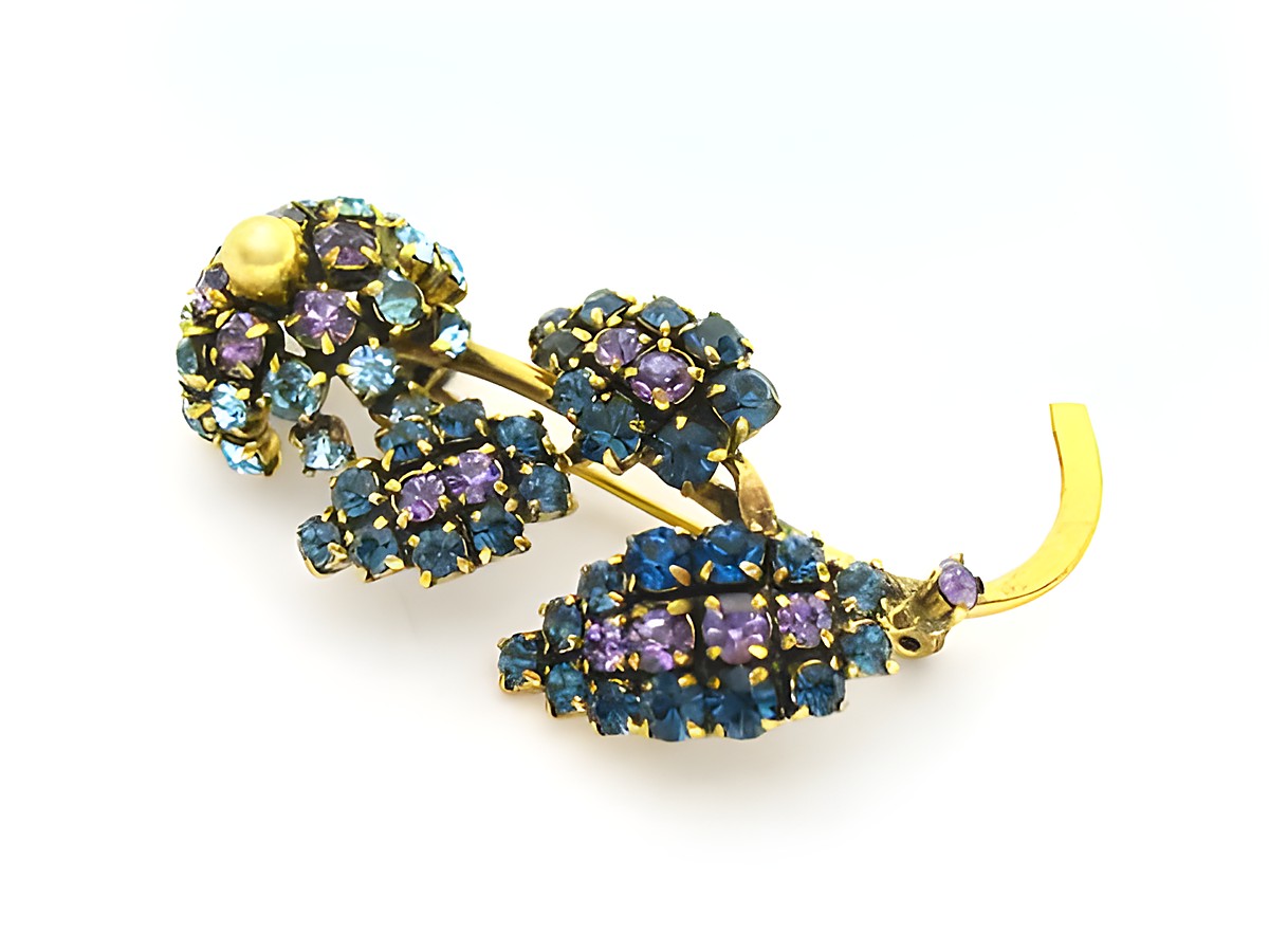 Brosche mit lila Blume im Sexy City Look, von Juwelier Harnisch, verziert mit Strasssteinen in verschiedenen Blau- und Lilatönen, elegantes Einzelstück für besonderen Anlass.